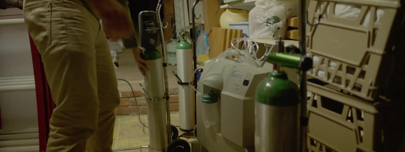 A teenager moves oxygen tanks in a supply room