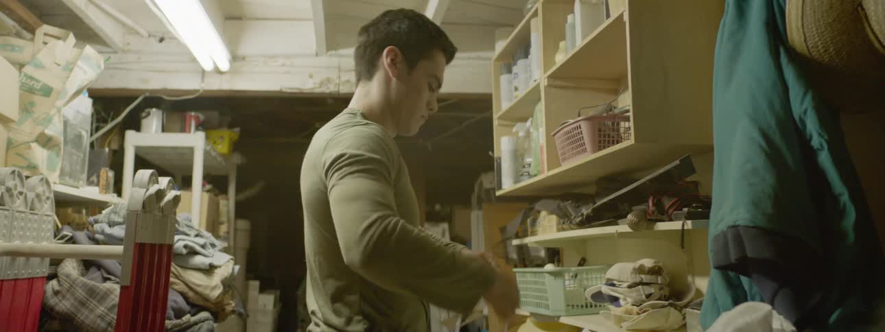 A white man stands in a crowded interior space and untangles a cord