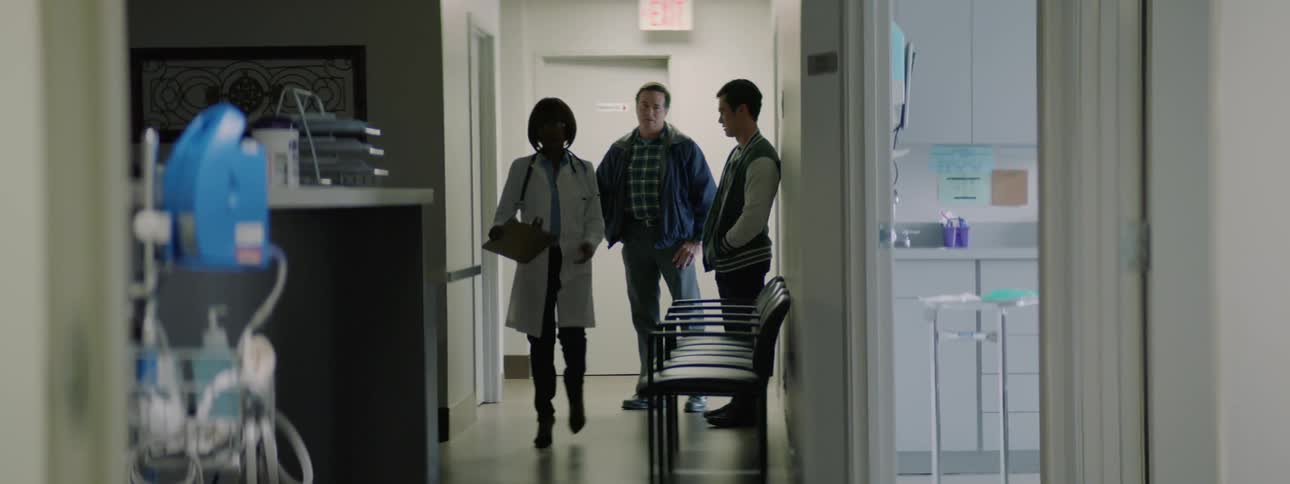 A doctor talks to a father and son and then the father puts his arm around his son