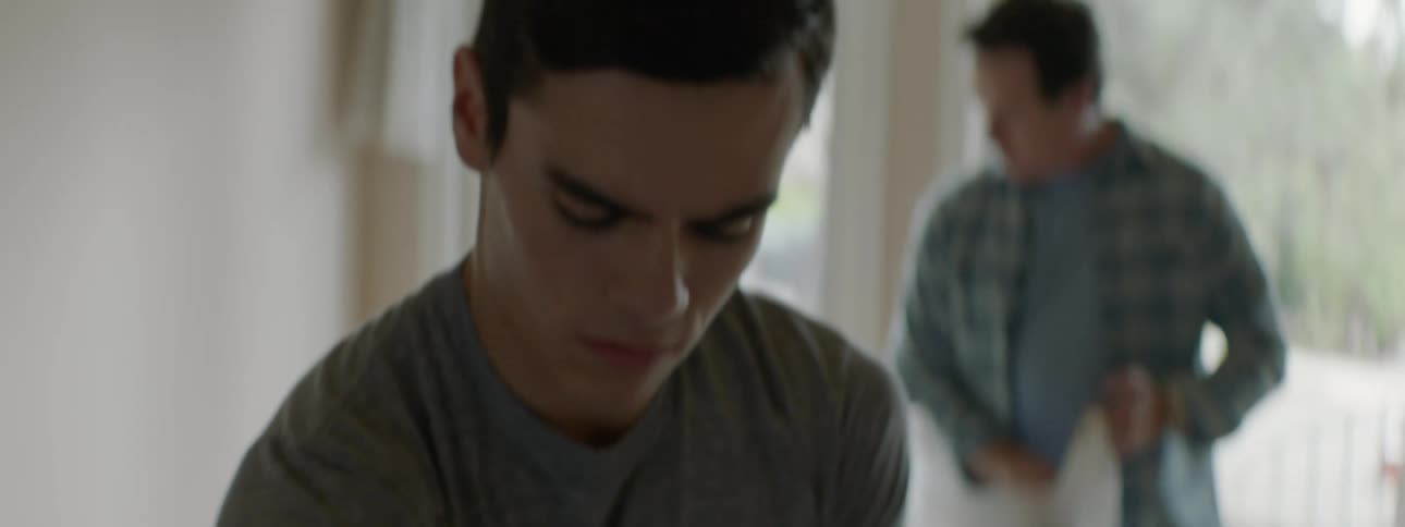 Teenage son tapes up a box while his father gathers things in a plastic bag