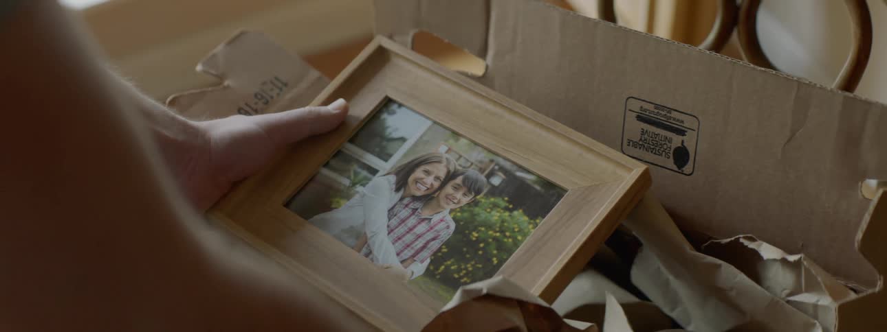 A person packing takes a moment to look at a family photo