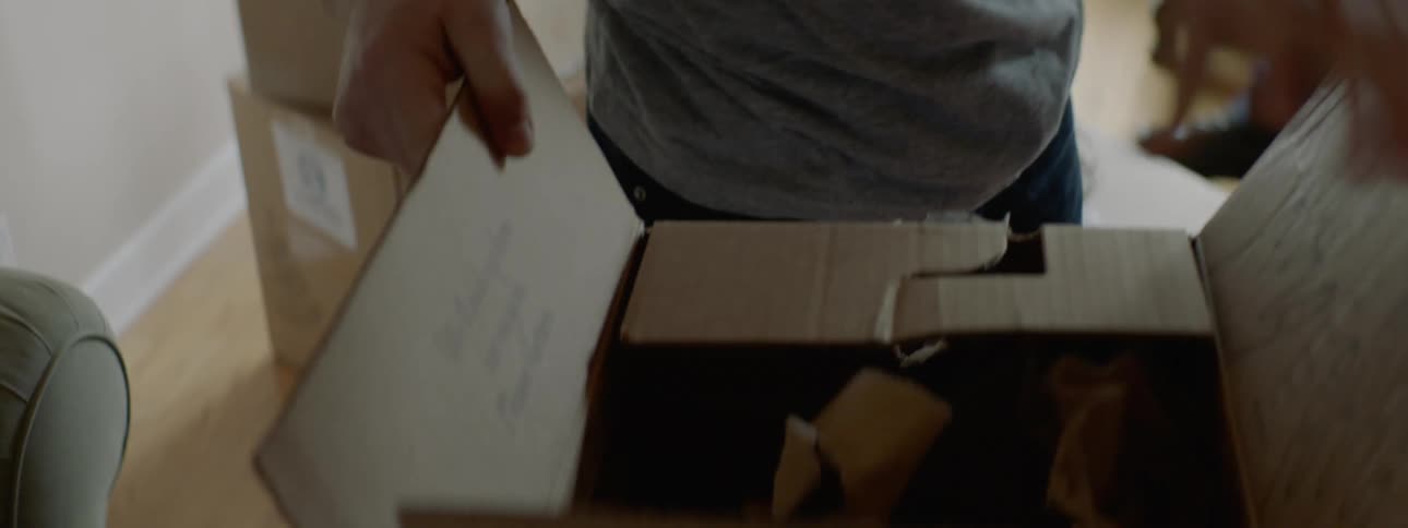 A man and his older son pack up boxes in a home