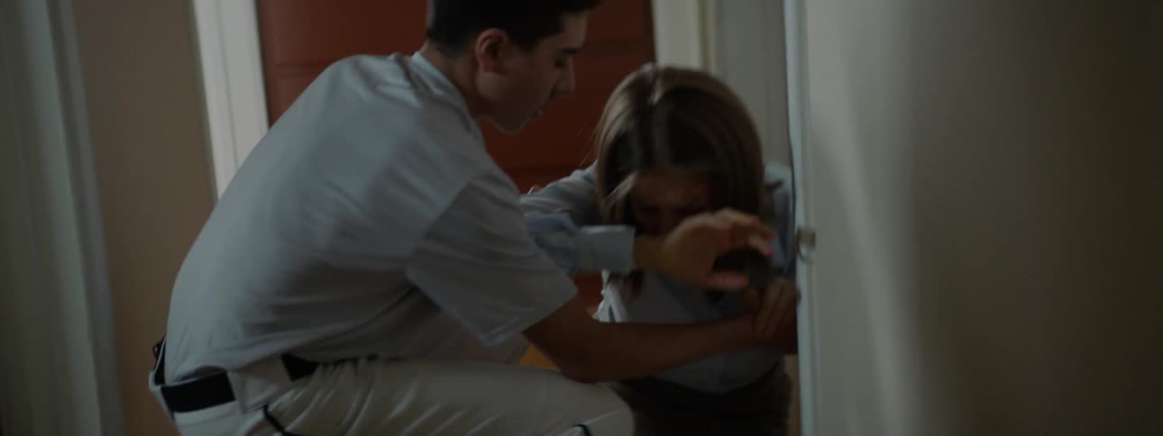 A man in a baseball uniform runs to help a white woman having a coughing fit