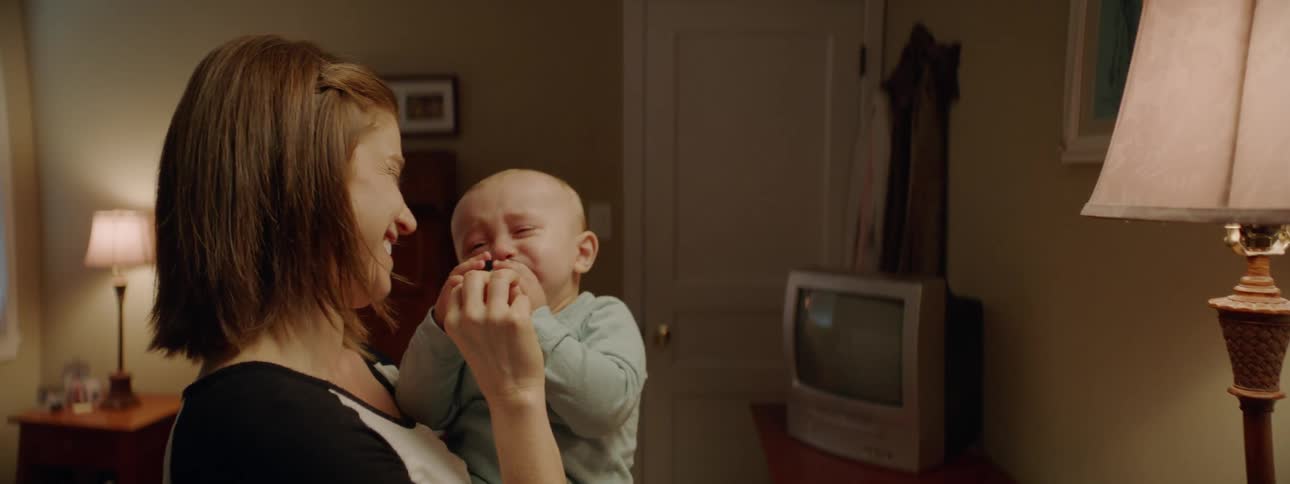 Mother holds baby in her arms in a dimly lit room