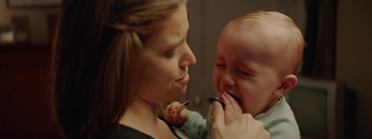 A mother is holding her baby indoors