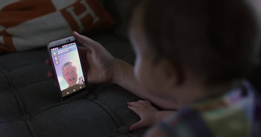 A mother and her son talk to a grandmother on a cell phone
