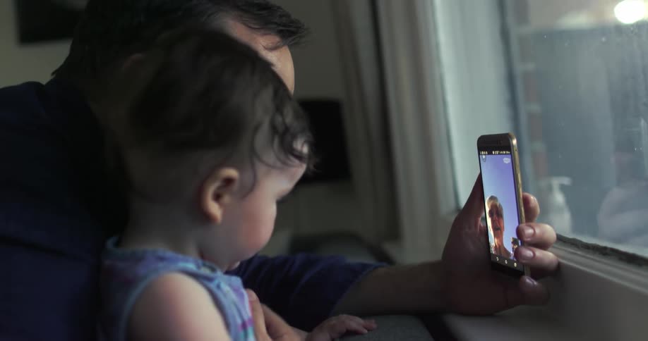 Father holds phone in front of her daughter in a video call