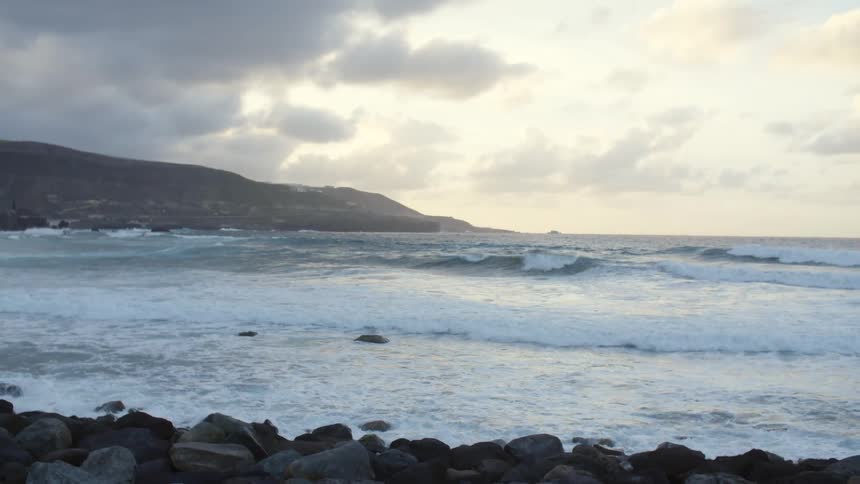 The waves slowly hit the rocks on the shore