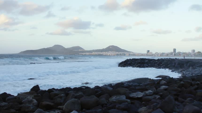 Waves rolling into the rocky coast outside of a city
