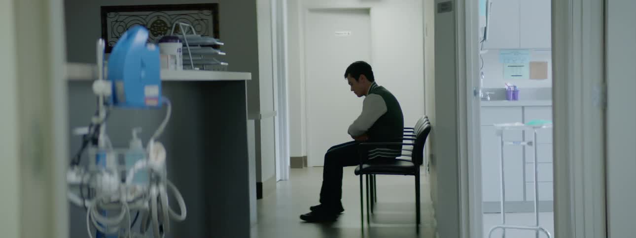 Young man sits on a chair in a clinic corridor