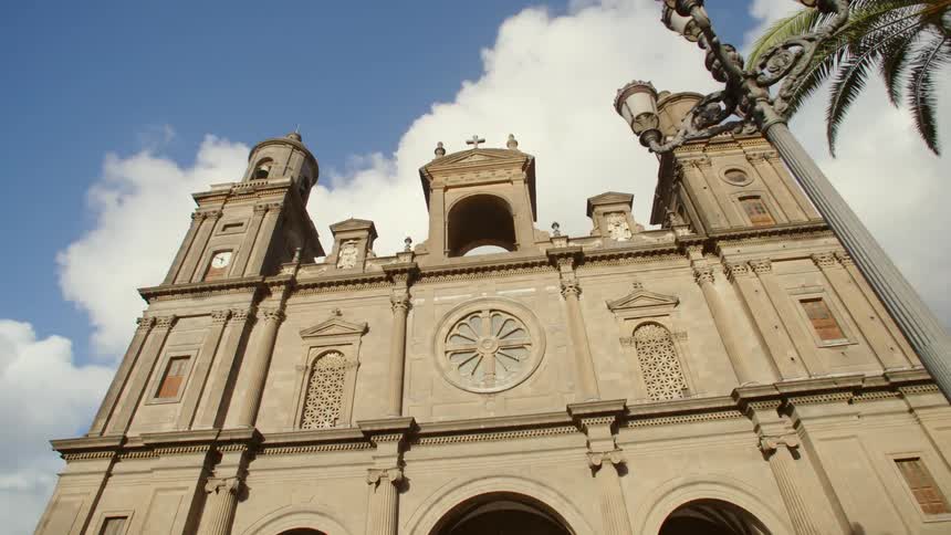 A church with a lamppost and a tree in the foreground and the sky and clouds in the background