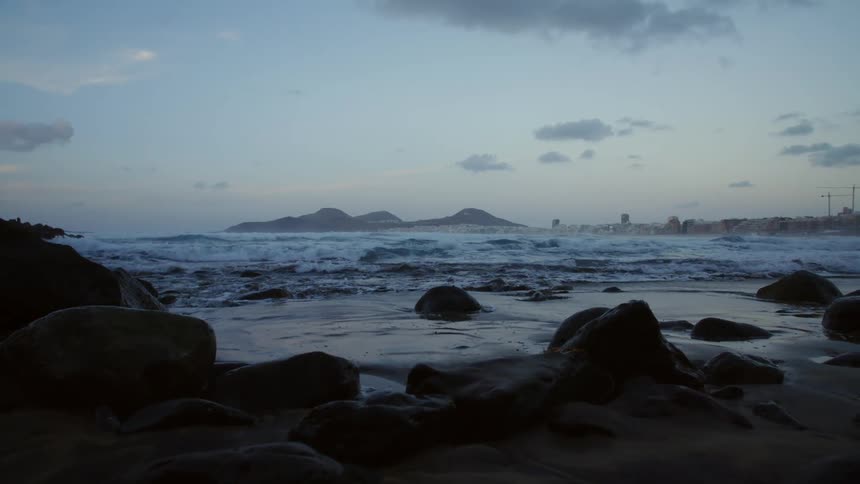 Waves splashing on rocky shoreline at night