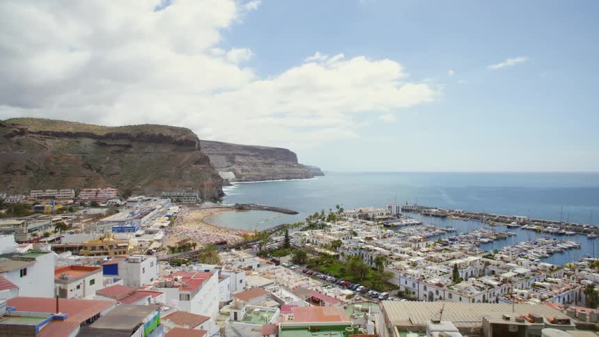 A city with a marina sits on the coast of an ocean
