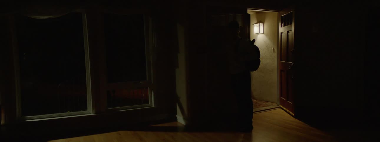 Man wearing a cap and backpack switches off the lights and goes out