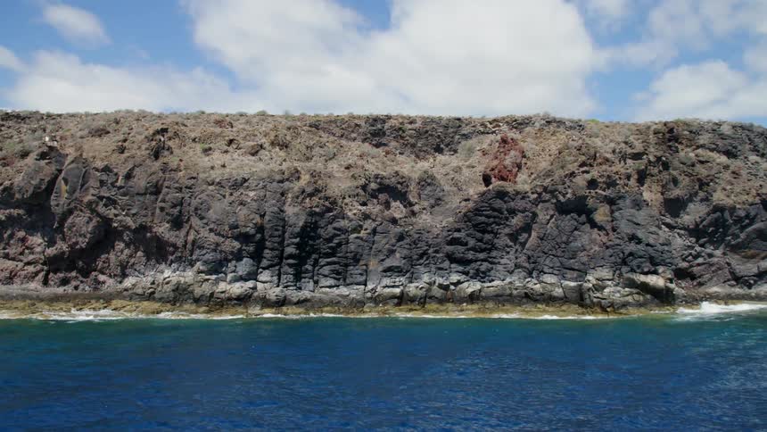 Cliffs on a coast next to blue ocean water under blue sky