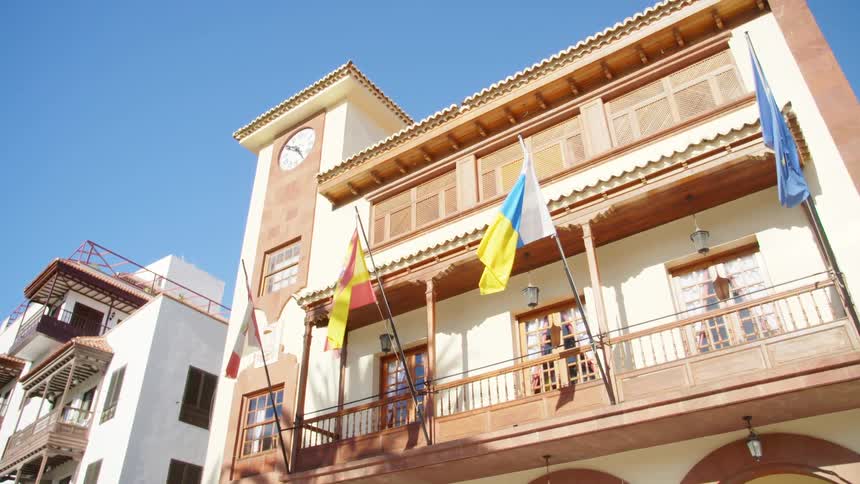 Flags fly outside a three story building in a neighborhood