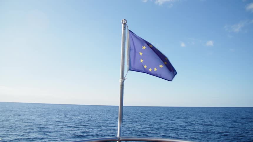 Blue flag with stars flies on a pole at the front of a boat in the ocean