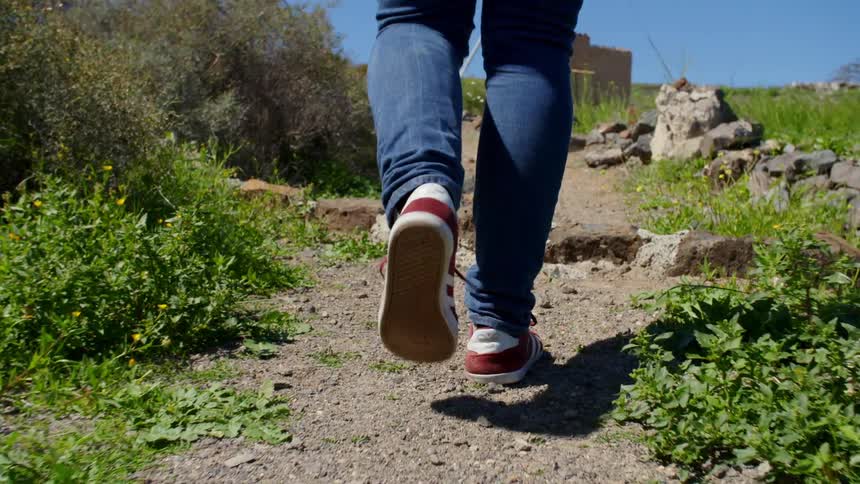 Red sneakers walking on a dirt path on a deserted field