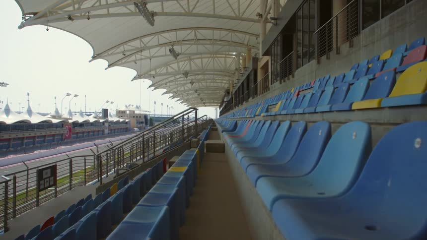 Empty blue seats under an awning in a stadium