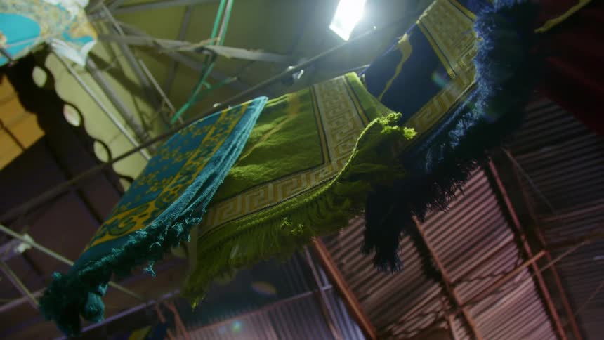 Folded rugs hanging on a cable on display