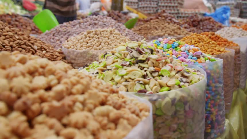 Open bins in a market are filled to the top with various nuts and candy