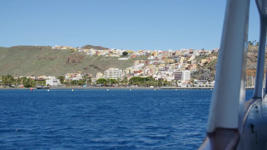 Boat sailing in the calm ocean waters towards the town of san sebastian de la gomera