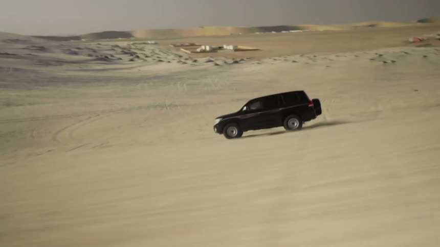 An suv traveling offroad down a sandy slope in a desert