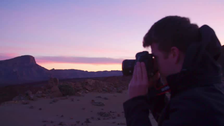 A young man takes pictures of the landscape at dusk