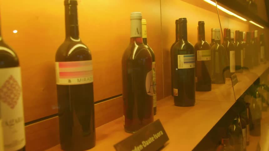 Wine bottles on wooden shelves enclosed by glass