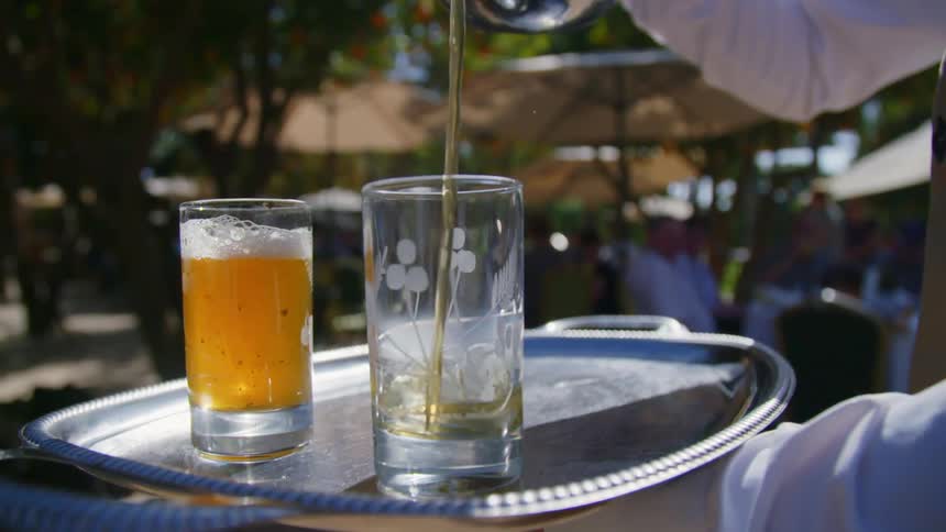 Server pouring a beverage from a pitcher into a glass