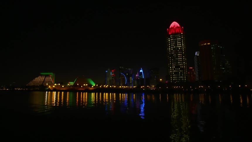 Skyline of the city with illuminated tall buildings reflected on water at night
