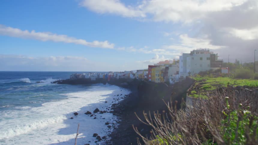 Waves rolling in to the coast with houses on the beach