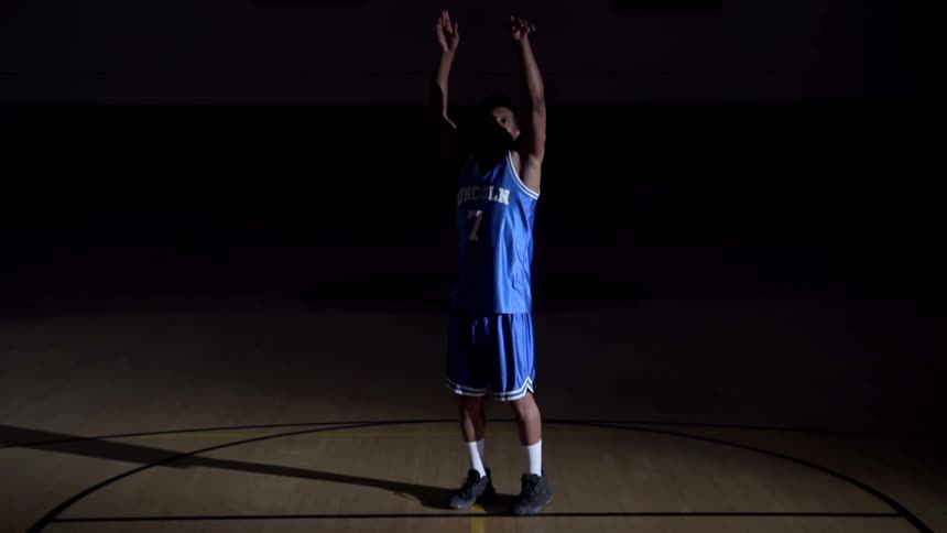 Basketball player standing on a basketball court shoots a basketball