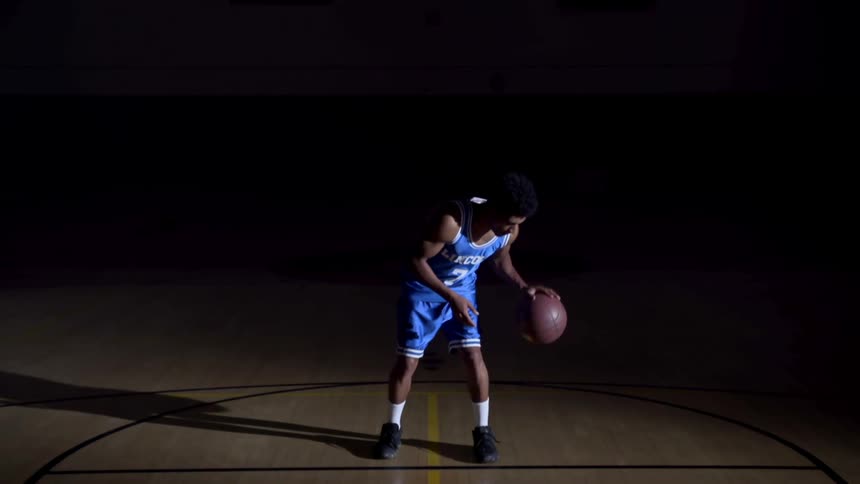 A teenager dribbles a basketball and spins it