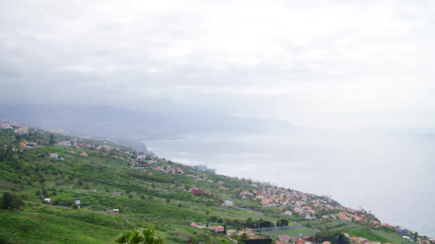 Coastal town with green hills on a cloudy day