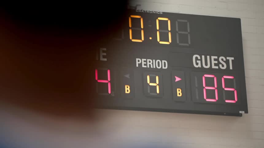 A person in front of a scoreboard