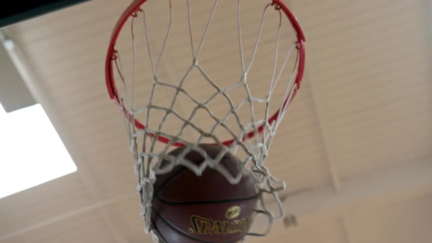 Worms eye view of a basketball going through a hoop
