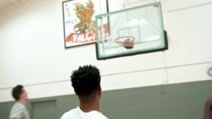 A black teenager takes a shot in a basketball practice