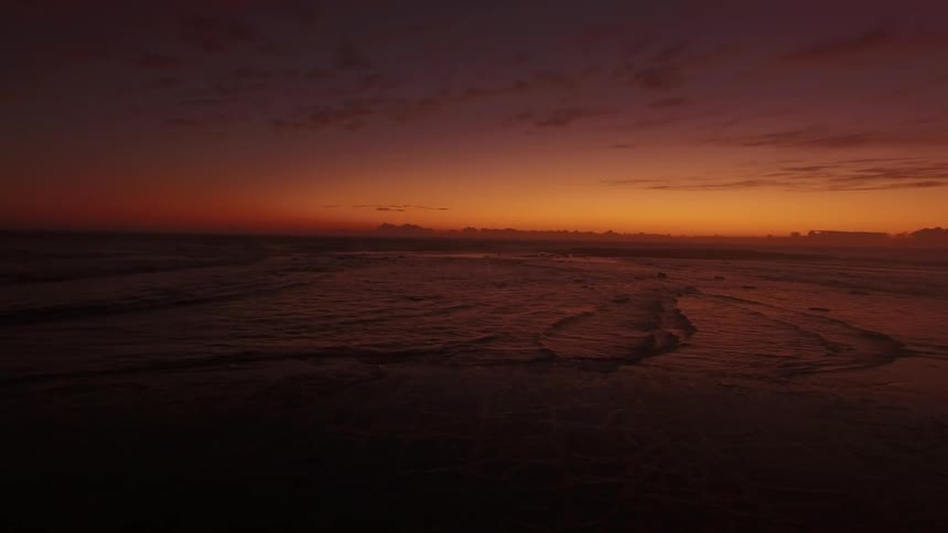 Ocean waves wash ashore at sunset