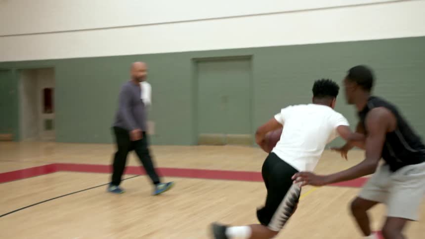 Man grabs a basketball and shoots it at the net and scores