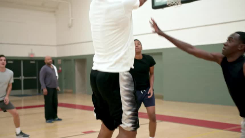 A group of young men play basketball in a gym