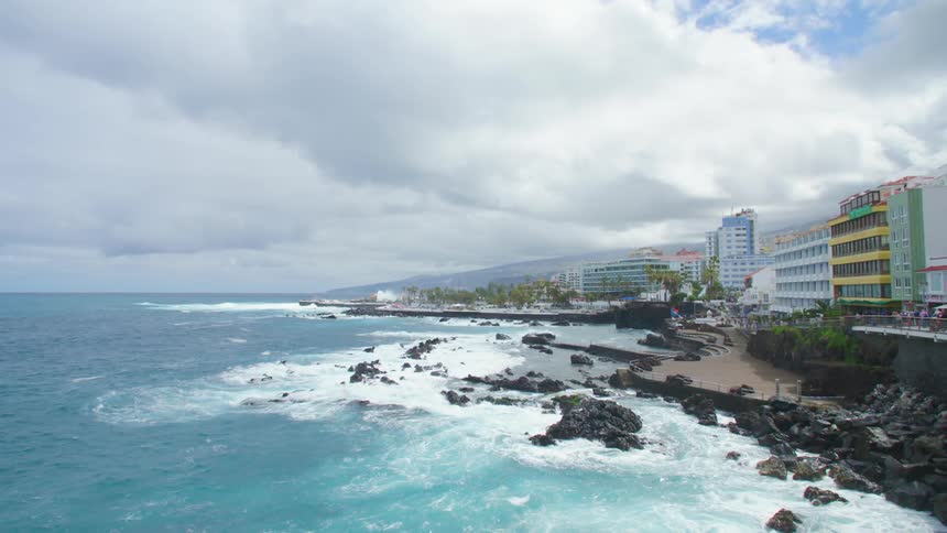 A rocky coast with trees buildings and the sky in the background
