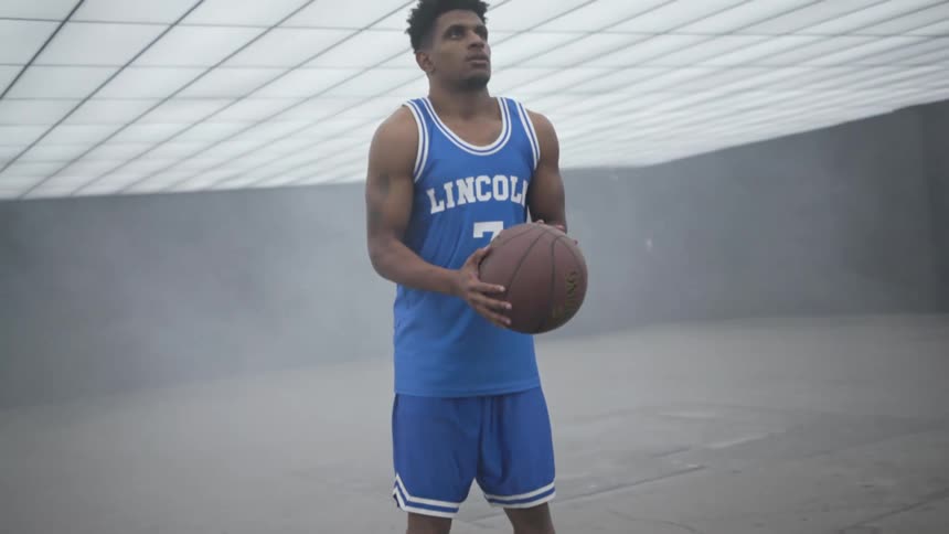 A teenager holds a basket ball and concentrates before throwing it