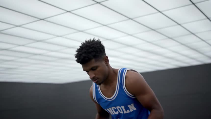 A teenager dribbling a basketball and getting ready to shoot