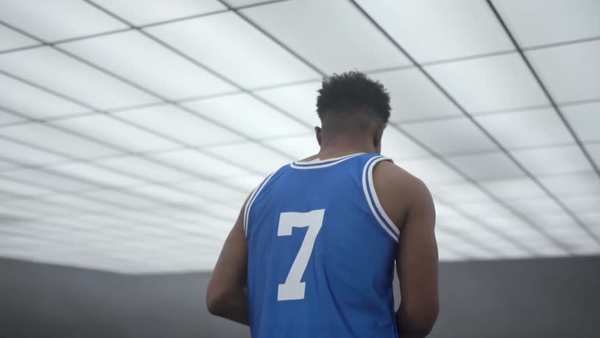 A black teenager dribbling a basketball inside