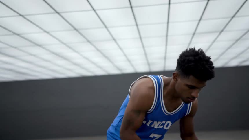 A basketball player takes a deep breath and starts to dribble the ball before shooting