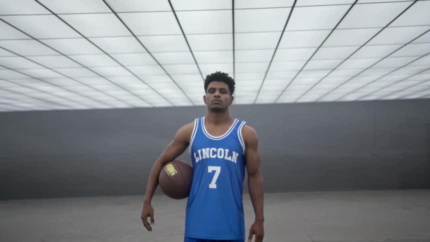 A man is standing still holding a basketball