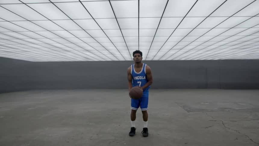 A basketball player dribbles In a futuristic room