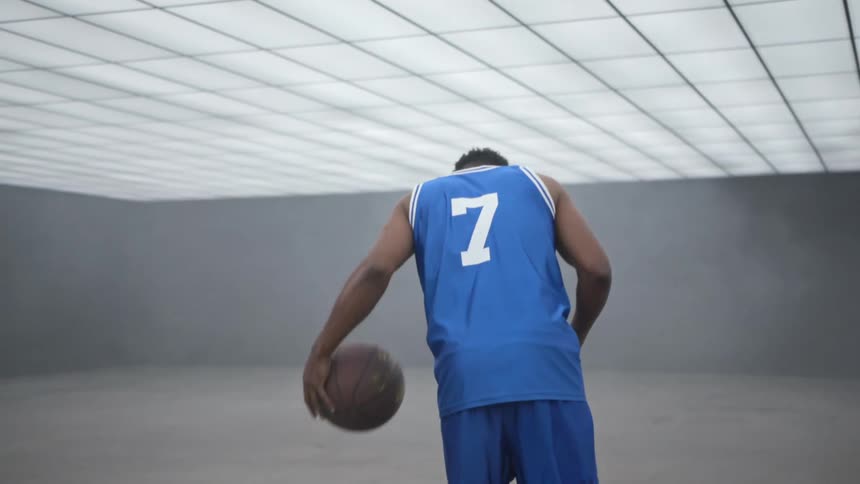A black teenager dribbles a basketball