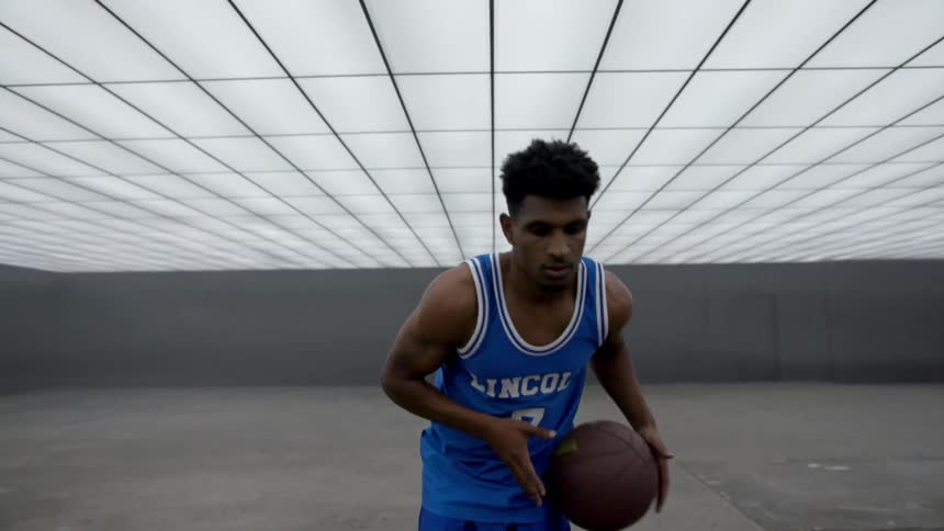 A basketball player dribbles In a futuristic room